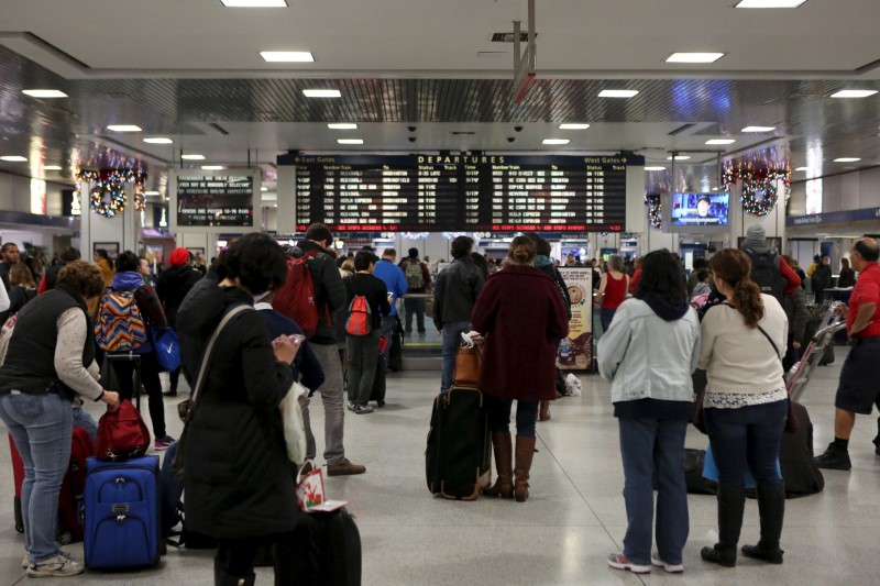 © Reuters. Travelers with suitcases wait for trains in Pennsylvania Station in Manhattan