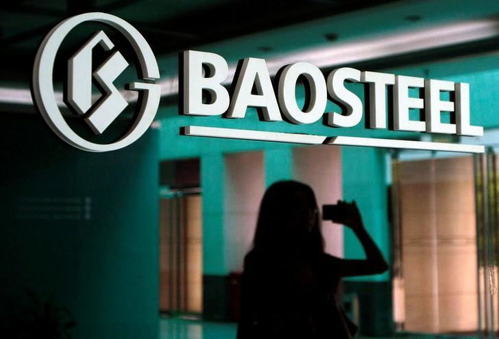 © Reuters. A woman is reflected on a wall with a company logo of Baosteel Group at an office in Shanghai