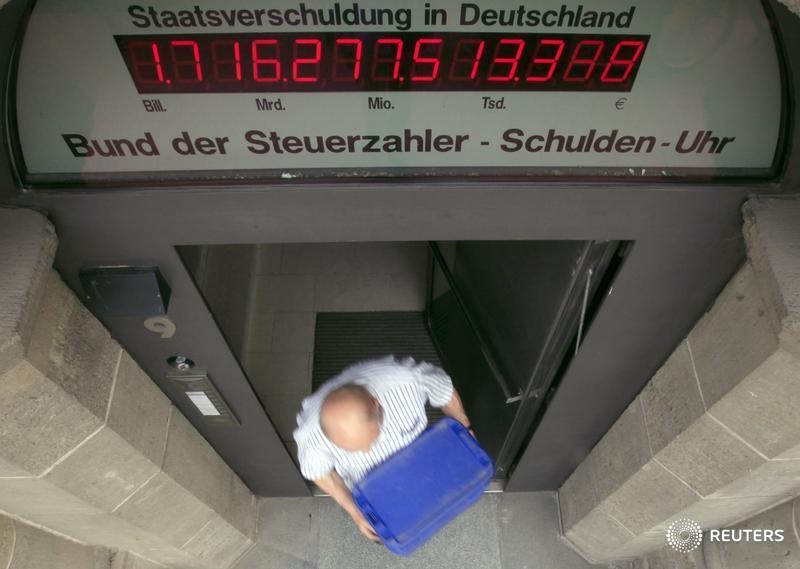 © Reuters. A man exits a building beneath Schuldenuhr debt clock in Berlin
