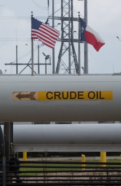 © Reuters. A crude oil pipe is seen with the American and Texas flags flying during a tour by the Department of Energy at the Strategic Petroleum Reserve in Freeport