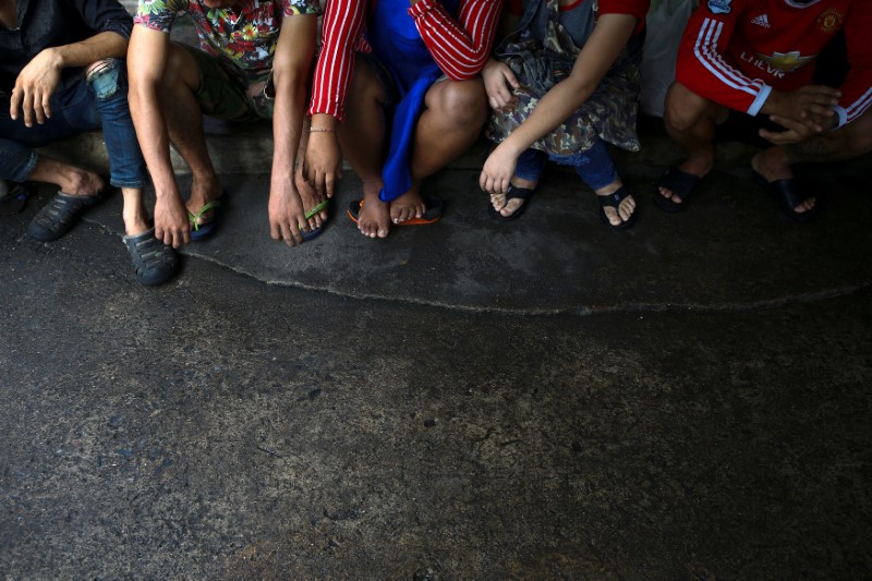 © Reuters. Migrant workers are detained by a military personnel during a crack down on illegal migrant workers at a market in Bangkok