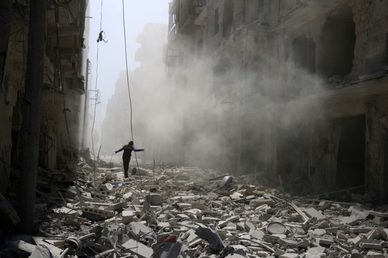 © Reuters. Homem caminha sobre destroços após ataque aéreo em bairro de Aleppo controlado por rebeldes