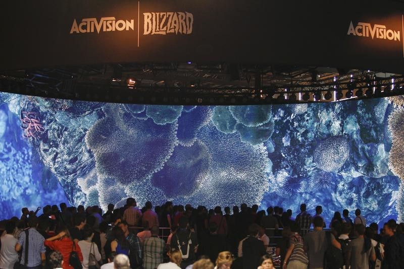 © Reuters. Visitors look at a presentation at the ActiVision Blizzard exhibition stand during the Gamescom 2013 fair in Cologne