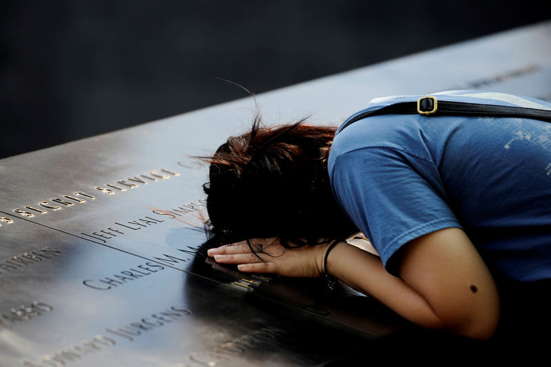 © Reuters. A woman lays her head on a row of names at the National September 11 Memorial, ahead of the 15th anniversary of the attacks in Manhattan, New York