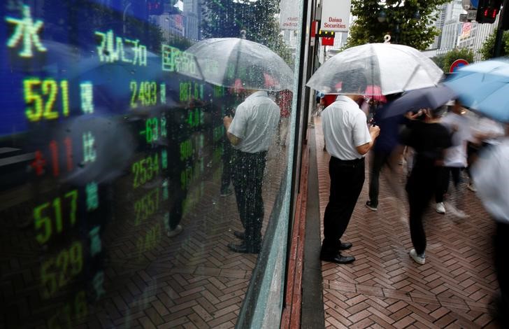 © Reuters. A man stands next to an electronic board showing stock prices in Tokyo