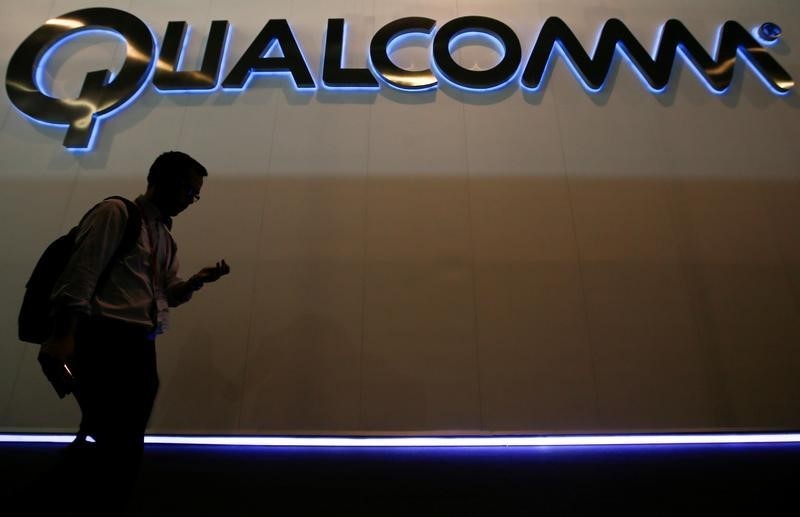 © Reuters. A man walks past Qualcomm stand while attending during the Mobile World Congress in Barcelona