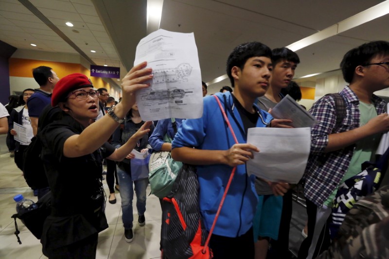© Reuters. Students enter a hall for SAT examinations beside a security guard at Asia-World Expo near Hong Kong Airport in Hong Kong