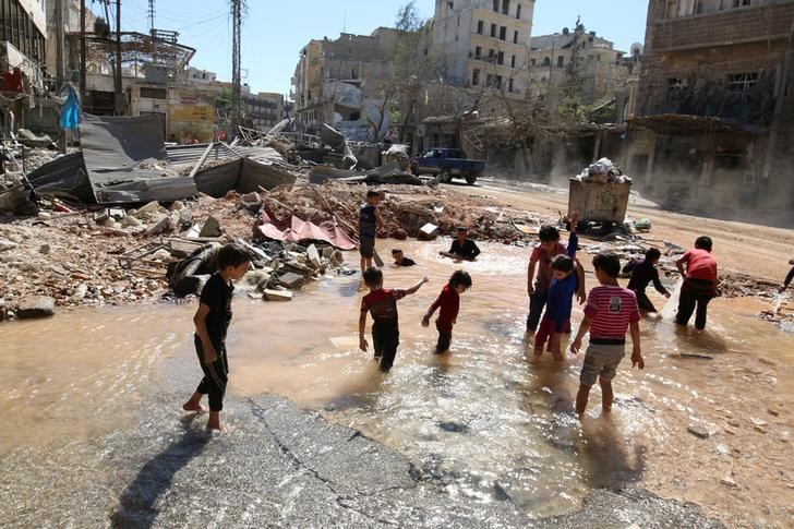 © Reuters. Crianças brincam em água de local atingido por ataque em bairro de Aleppo