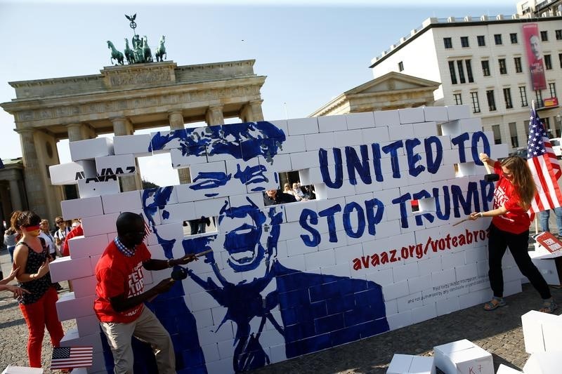 © Reuters. Campaigners pose on a 'United To Stop Trump' cardboard wall in front of the Brandenburg Gate to urge Americans living abroad to register and vote in Berlin