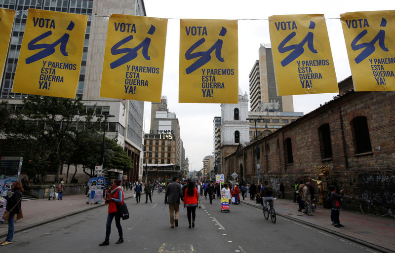 © Reuters. Pedestrians walks under a banner supporting Colombian plebiscite in downtown in Bogota