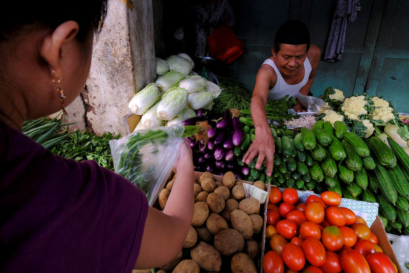 © Reuters. A vegetable vendor takes money from customer at a morning market in Jakarta