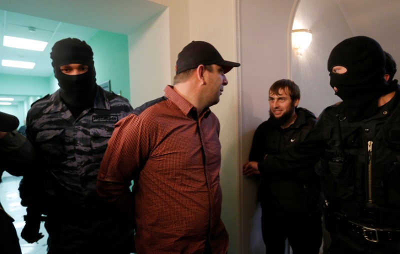 © Reuters. Eskerkhanov who is suspected of involvement in killing of opposition figure Nemtsov is escorted by police officers upon his arrival to trial in Moscow