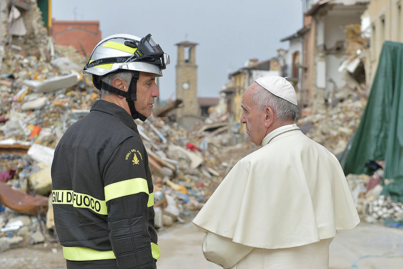 © Reuters. Pope Francis talks with a firefighter in Amatrice