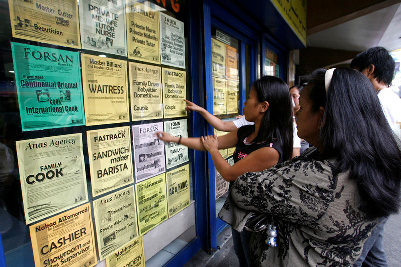 © Reuters. File photo shows applicants looking at job offers displayed on a glass window of a recruitment agency in Manila