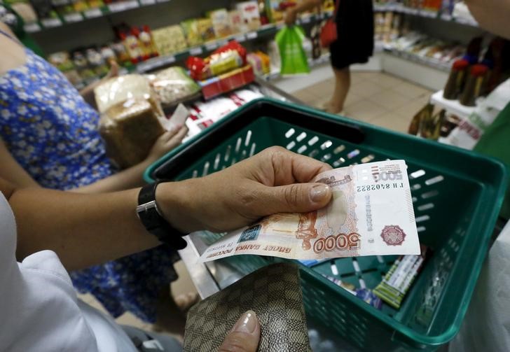 © Reuters. Покупательница в продуктовом магазине Красноярска держит купюру в 5000 рублей