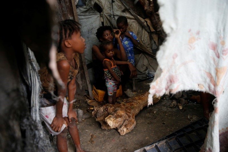 © Reuters. Members of a family warm themselves next to a fire while Hurricane Matthew approaches Port-au-Prince