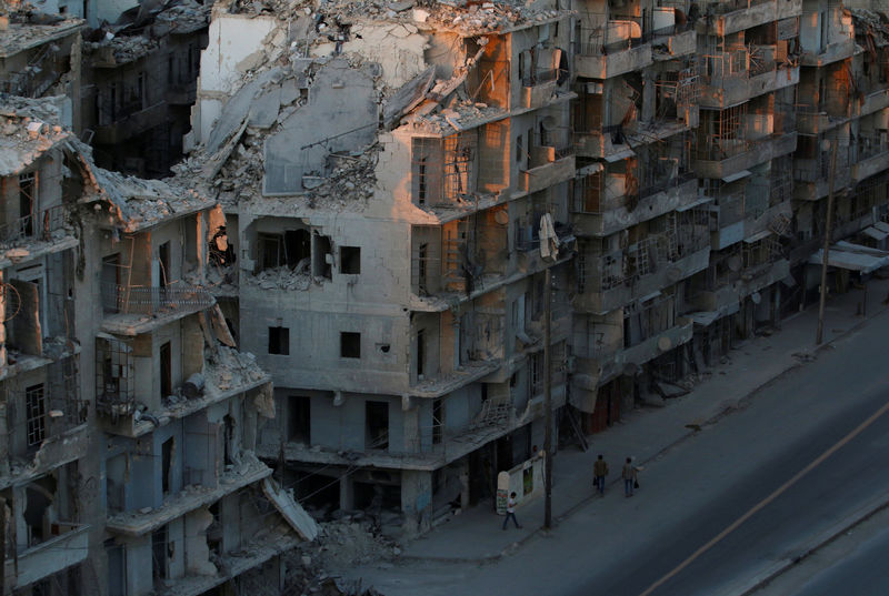 © Reuters. People walk past damaged buildings in the rebel-held Tariq al-Bab neighbourhood of Aleppo