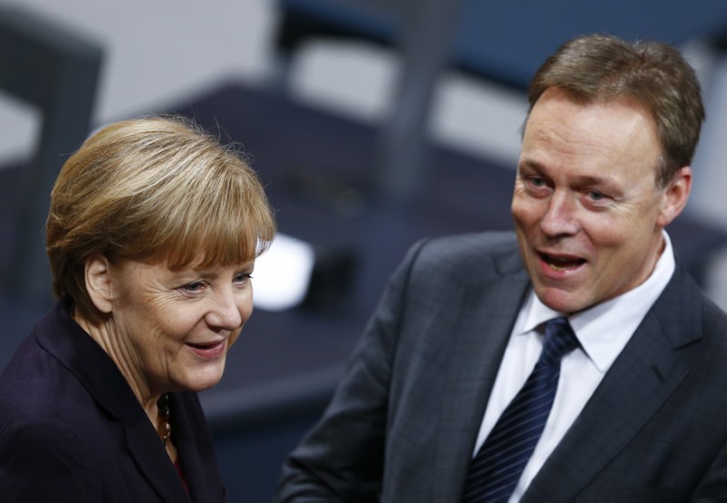 © Reuters. Parliamentary faction leader of Germany's SPD Oppermann reacts next to German Chancellor Merkel during a session of the lower house of parliament Bundestag in Berlin