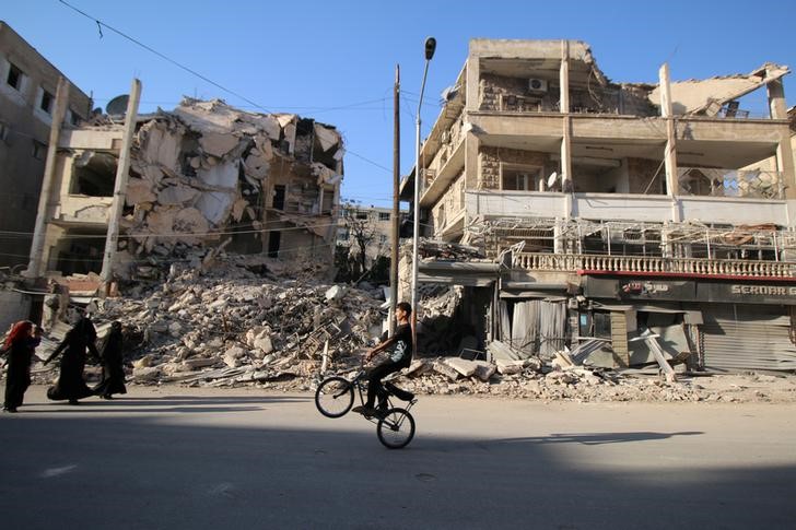 © Reuters. Garoto em bicicleta diante de edifícios destruídos em Aleppo