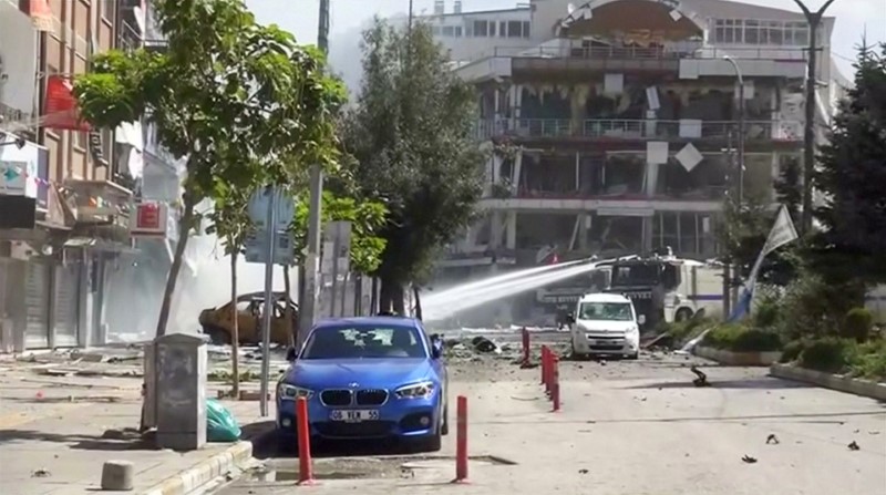 © Reuters. A water cannon sprays in front of damaged buildings and vehicles after suspected Kurdish militants detonated a car bomb near local government offices in Turkey's southeastern city of Van