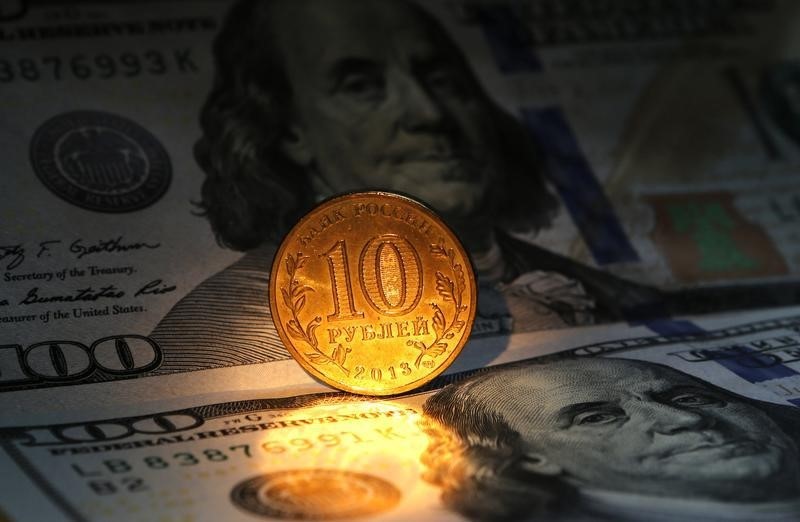 © Reuters. Десятирублевая монета на фоне стодолларовых купюр