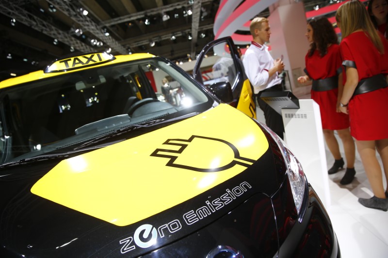 © Reuters. Models stand beside a Nissan zero emission taxi "e-NV200" at Frankfurt Motor Show