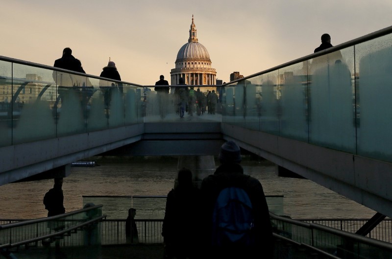 © Reuters. File photo of city workers walking towards St Paul's Cathedral as they cross the Millennium footbridge during sunrise in central London