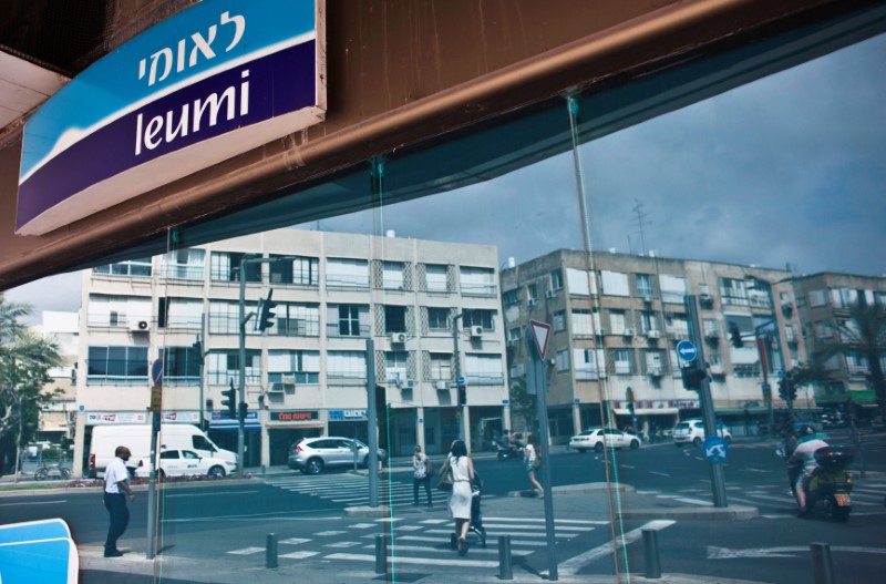 © Reuters. Pedestrians are reflected in the windows of a branch of Bank Leumi, Israel's second-largest lender, in Tel Aviv, Israel