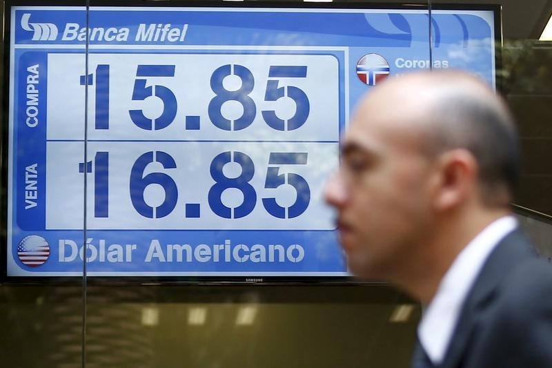 © Reuters. A man is passes in front of a board displaying the exchange rate for peso and U.S. dollars at a foreign exchange house in Mexico City
