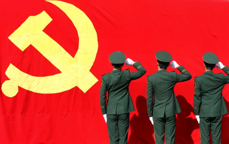 © Reuters. Paramilitary policemen hold their fists in front of a flag of Communist Party of China as they attend an oath-taking rally to ensure the safety of the upcoming 18th National Congress of the Communist Party of China, at a military base in Hangzhou