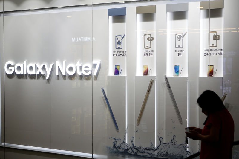 © Reuters. A woman talking on her mobile phone walks past an advertisement promoting Samsung Electronics' Galaxy Note 7 at the company's headquarters in Seoul