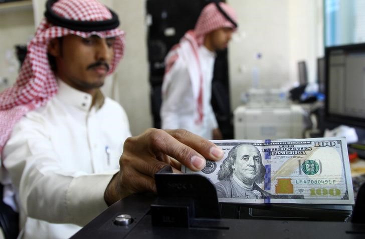 © Reuters. Сотрудник пункта обмена валют в эр-Рияде пересчитываят доллары