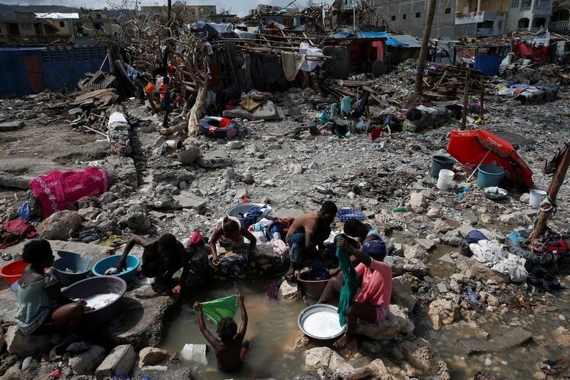 © Reuters. Pessoas lavam roupas perto de casas destruídas após furação atingir Jeremie, no Haiti