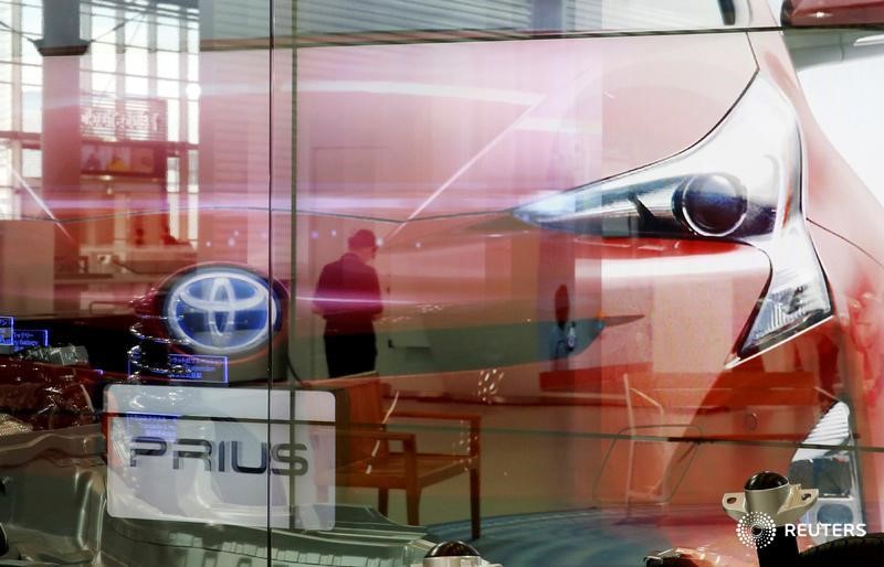 © Reuters. Woman is reflected on a screen showing Toyota Motor Corp's Prius hybrid car at the company's showroom in Tokyo