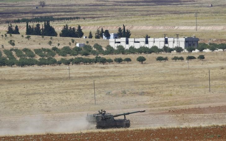 © Reuters. A Turkish Army military vehicle, with the Syrian town of Kobani in the background, patrols on the Turkish-Syrian border in Suruc in Sanliurfa province