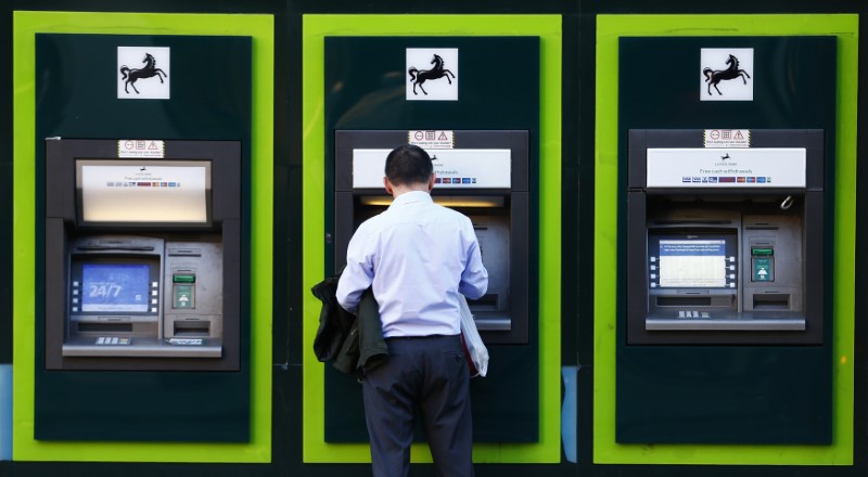 © Reuters. A man uses an ATM  outside a branch of Lloyds Bank in central London