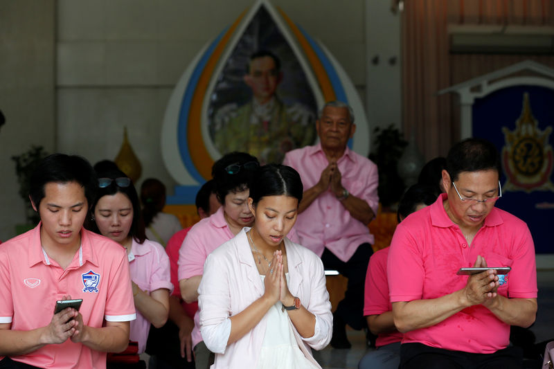 © Reuters. Well-wishers wear pink shirts as they pray in front of a picture of Thailand's King Bhumibol Adulyadej at Siriraj Hospital in Bangkok