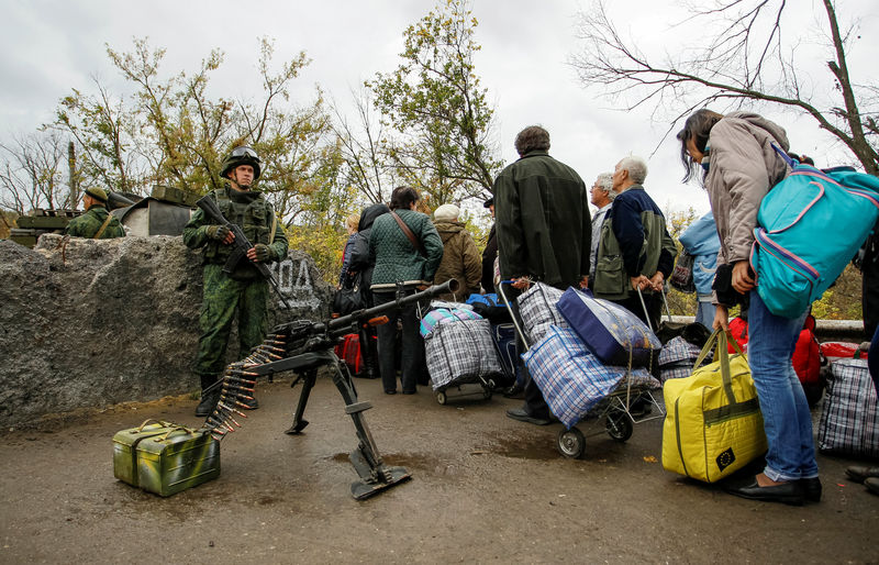 © Reuters. Members of the self-proclaimed Luhansk People's Republic forces stand guard as residents queue at pass through a check point located on the troops contact line between pro-Moscow rebels and Ukrainian troops, in Luhansk region