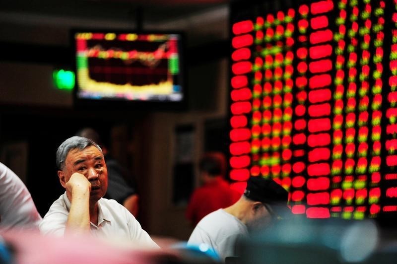 © Reuters. An investor sits in front of an electronic board showing stock information at a brokerage house in Nanjing
