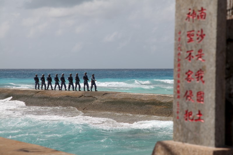 © Reuters. Soldiers of China's People's Liberation Army (PLA) Navy patrol near a sign in the Spratly Islands, known in China as the Nansha Islands