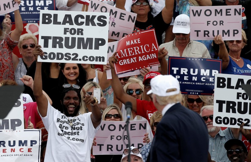 © Reuters. Republican U.S. presidential nominee Donald Trump looks back at supporters holding signs at a campaign rally in Lakeland