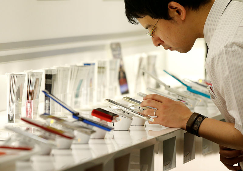 © Reuters. Man looks at mobile phones at the SoftBank Group Corp's headquarters in Tokyo