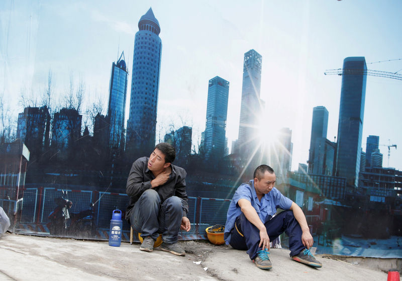 © Reuters. Workers rest outside a construction site in Beijing's central business district