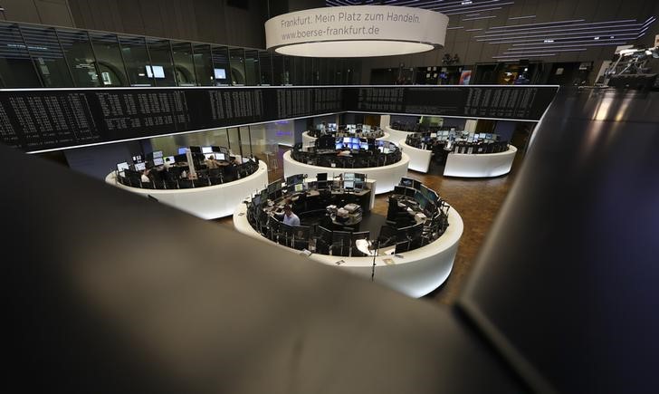 © Reuters. Traders work at their desks in front of the German share price index, DAX board, at the stock exchange in Frankfurt