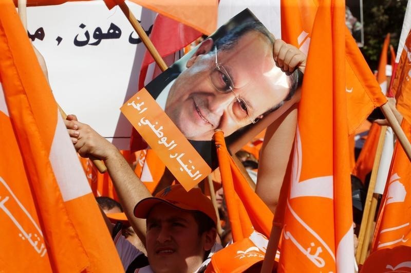 © Reuters. Supporters of the Free Patriotic Movement (FPM) carry flags and a picture of Christian politician and FPM founder Michel Aoun during a rally to show support for Aoun and calling to elect a president, near the presidential palace in Baabda