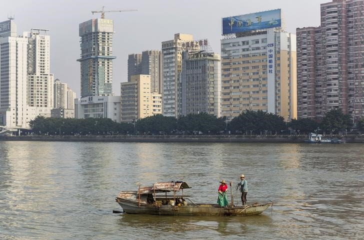 © Reuters. A couple fishing along Pearl River next to office buildings in downtown Guangzhou