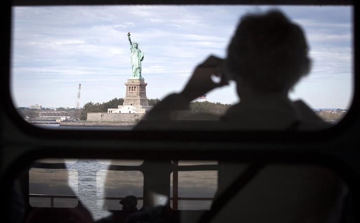 © Reuters. The Statue of Liberty is pictured from the Staten Island Ferry as people are reflected in windows in New York