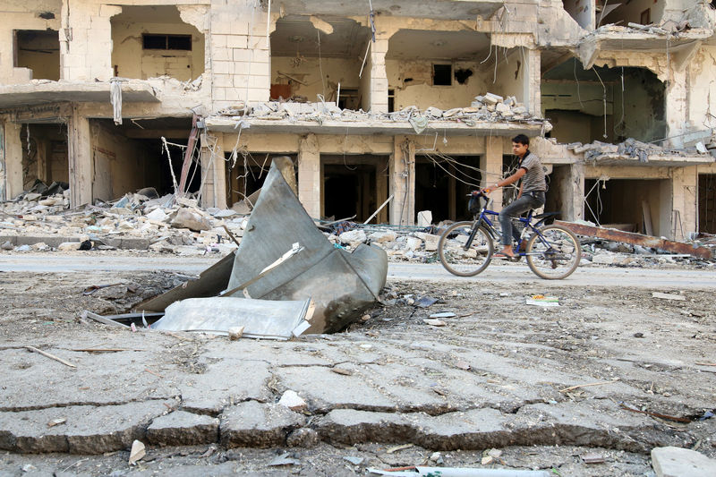 © Reuters. A man rides a bicycle near damaged ground in the rebel held besieged al-Sukkari neighbourhood of Aleppo