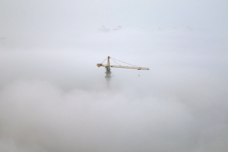 © Reuters. A crane is seen among thick fog in Yantai