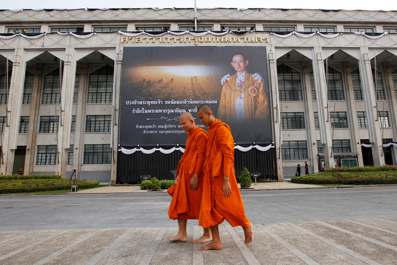 © Reuters. Buddhist monks walk past a portrait of Thailand's late King Bhumibol Adulyadej outside Bangkok City Hall